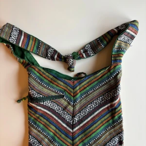 Färgglad axelväska med mönster - Säljer en färgglad axelväska med ett unikt mönster i grönt, rött, blått och vitt. Väskan har en praktisk dragkedja och en justerbar axelrem. Perfekt för att ge din outfit en bohemisk touch!