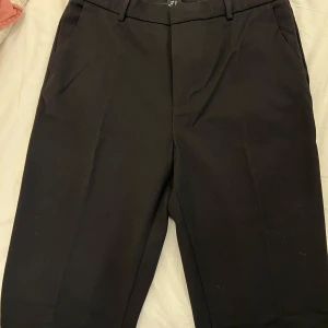 Kostymbyxor Stockh lm från MQ 40L - Härlig kostymbyxa av hög kvalité. Rak passform med knapp och hyska i midjan. Modellen har en normal midja och är extra långa i benen. 