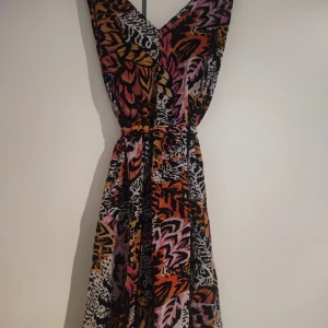 Mönstrad klänning från & Other Stories - Snygg mönstrad klänning från & Other Stories i djärva färger som orange, rosa och svart. Klänningen har ett vackert mönster som påminner om djurprint och en v-ringad design. Perfekt för att sticka ut med stil!