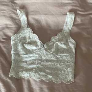 Vit spetslinne från Amisu - Säljer en söt vit spetslinne från Amisu. Den har breda axelband och är täckt av vacker spets. Perfekt för att lägga till en romantisk touch till din outfit. 💕