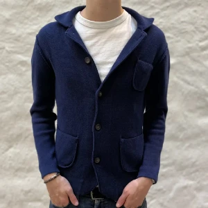 Mörkblå stickad kavaj - Snygg mörkblå stickad kavaj med knappar framtill. Den har långa ärmar och tre praktiska fickor. Perfekt för en stilren look.