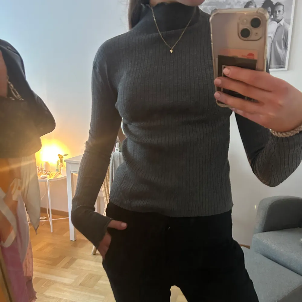 Säljer en stilren grå ribbad polotröja från Zara. Tröjan har en tight passform och långa ärmar, perfekt för kyligare dagar. Den är tillverkad i ett mjukt material som ger en bekväm känsla. Passar utmärkt till både jeans och kjol.. Neuletakit & Villapaidat.