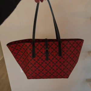 Röd och svart shoppingväska från By Malene Birger - Röd väska med blå detaljer från Marlene Birger. Jag har haft den i ca fem år men är knappt använd så den är i ett mycket fint skick! Säljs eftersom den inte kommer till användning.  Bredden längst upp : ca 40  Höjd: ca 20 cm