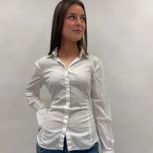 Vit långärmad skjorta med knyt - Snygg och klassisk vit skjorta med långärmade ärmar och knappar framtill. Perfekt för en stilren look. Skjortan har en normal passform och är tillverkad i ett bekvämt material.