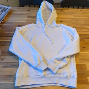 Vit hoodie från Zara - Säljer en stilren vit hoodie från Zara. Den är tillverkad i 99% bomull och 1% elastan, vilket ger en mjuk och bekväm känsla. Hoodien har en klassisk design med känguruficka och justerbar huva med dragsko. Liten fläck på bröstet som inte syns så mycket. Går o ta bort i tvätten säkert