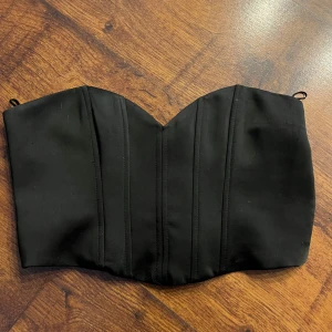 Svart tubtopp - Snygg svart tubtopp från Zara med en stilren design. Toppen har en smickrande passform med en elastisk del baktill för extra komfort. 