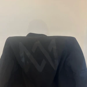 Marcus och Martinus Jacka - Jag Säljer en svart jacka från MM Store med en ”Marcus och Martinus” logga på ryggen. 🌸Jackan har en dragkedja framtill och en orange insida. Den är i super bra skick och använd 2 gånger.🌸