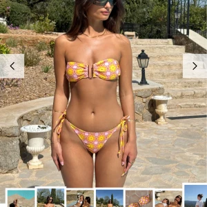 Färgglad bikini med mönster - Snygg bikini med ett färgglatt mönster i rosa och gult. Överdelen är bandeau med knytband och en ringdetalj i mitten. Underdelen har knytband på sidorna för justerbar passform. Säljer pga för liten. Nypris 378