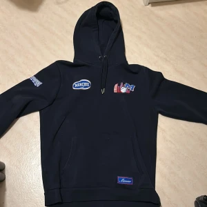 Svart hoodie från Mercier - Säljer en svart hoodie från Mercier med tryck på bröstet och ryggen. Hoodien har en klassisk design och justerbar huva. 