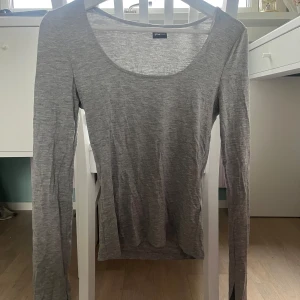 Grå långärmad tröja från Gina Tricot - Säljer en stilren grå långärmad tröja från Gina Tricot. Perfekt för en avslappnad look, med en mjuk och bekväm passform. Tröjan har en rund halsringning och är tillverkad i ett lätt material. Det är slits i slutet av ärmarna! 