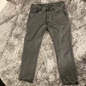 Grå Levis 501 jeans - Snygga grå Levis 501 jeans i klassisk design. De har en rak passform och är tillverkade i slitstarkt denim. Perfekta för en stilren look med fem fickor och knappgylf. Köpte dom i Irland så har ej kvar kvittot.