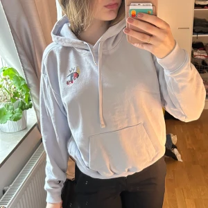 Ljusblå hoodie från Champion - Säljer en ljusblå hoodie från Champion med en logga på bröstet och en mindre logga på ärmen. Loggan på bröstet har skadats lite i tvätten.