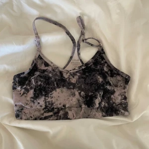 Mönstrad sporttopp från Casall - Säljer en snygg sporttopp från Casall i storlek XS. Toppen har ett unikt mönster i svart och grått med justerbara axelband. Perfekt för träning eller en aktiv vardag.
