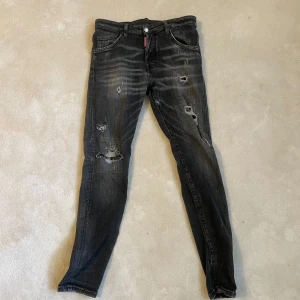 Svarta jeans från Dsquared2 - Snygga svarta jeans från Dsquared2 med slitna detaljer och en cool tvätt. De har en klassisk femficksdesign och knappgylf. Perfekta för en trendig look.