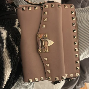 Beige axelväska från Valentino - Snygg beige/rosa väska från valentino. den e sliten men fortfarande super snygg obs den har gått sönder i en av remmarna men de går att laga  nypris- 17,300kr. har dock inget äktehetsbevis så kan ej garantera något den har flertal defekter så man är medveten om det!💗