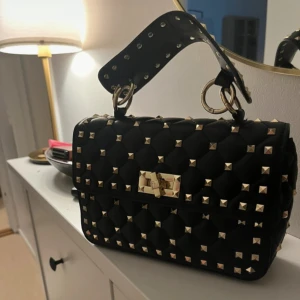 Svart quiltad handväska med nitar - Säljer denna superfina inspirerade  Va*en*ino väska, superbra kvalitet, superbra material. Inga skador, får plats med mycket. PRIS KAN DISKUTERAD VID SNABB AFFÄR