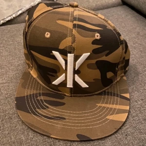 Camouflage keps från OnePiece - Aldrig använd, skickas i original box. Snygg keps i camouflage från OnePiece med broderad logga framtill. Perfekt för en cool och avslappnad stil. Justerbar passform för optimal komfort.