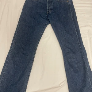 Levis 501 Blå jeansbyxor - Klassiska blå jeansbyxor med rak passform. De har en traditionell femficksdesign och är tillverkade i slitstarkt denim. Perfekta för en avslappnad stil.