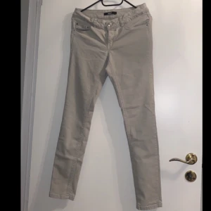 Beige chinos - Snygga beige chinos med normal passform och knappar framtill. Perfekta för en stilren look.