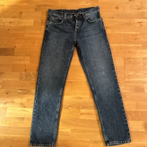 Blå jeans från Nudie Jeans - Snygga blå jeans från Nudie Jeans med klassisk femficksdesign och orange söm på bakfickan. Perfekta för en avslappnad stil.
