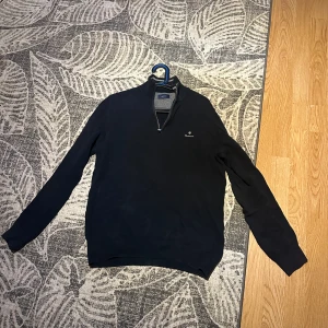 Halfzip tröja från Gant - Säljer en stilren svart/mörkblå tröja från Gant med dragkedja vid halsen. Skicket är 9/10 och inte använt många gånger alls. Säljer den pga av att den är för liten. Storlek M och nypris är runt cirka 1200 kr. Kontakta mig vid fler frågor eller om pris.