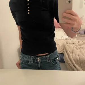 Mörkblå topp från Holly & Whyte - Snygg mörkblå topp från Holly & Whyte med korta ärmar och knappar framtill. Den har en ribbad kant och en liten volangdetalj vid halsen. Lite tajt för mig, andvöbder ibge längre. Jätte bra skick då den inte är så gammal och knappt andvänd