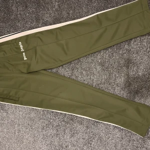 Trackpants från Palm Angels, byxor - Snygga olivgröna trackpants från Palm Angels. Knappt använda så i väldigt bra skick!