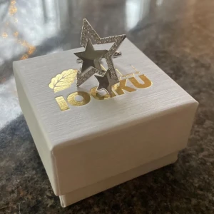 Silverfärgad stjärnring Ioaku - Trendig ring i silverfärg från Ioaku med dubbla stjärnor, en mindre och en större. Den större stjärnan är glittrig och ger en extra touch av glamour. Perfekt för att lysa upp vilken outfit som helst! Nypris 599kr ❤️🥰🩷 Pris kan diskuteras!
