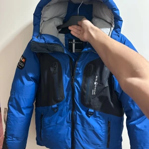  Sail Racing goretex vinterjacka  - Snygg blå dunjacka från Sail Racing med svarta detaljer och flera praktiska fickor. Jackan har en justerbar huva och dragkedja framtill. Perfekt för kalla dagar. Tjock och varm. Storlek M, passar L också enkel passform 