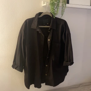 Svart skjorta från 157 - Snygg svart skjorta från 157 med klassisk krage och knappar framtill. Skjortan har långa ärmar och en bröstficka. 