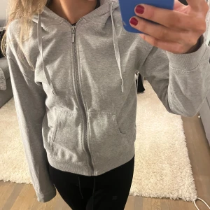Grå kofta - Säljer en stilren grå kofta med dragkedja och huva. Den är i väldigt bra skick då den endast används ett fåtal gånger. Storlek XS. Tveka inte att lägga prisförslag eller ställa frågor!