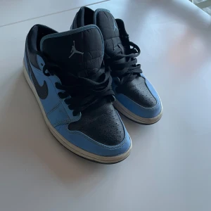 Nike Air Jordans i blått och svart - Snygga Nike Air Jordans i en fräsch kombination av blått och svart. Skorna har klassisk snörning och en ikonisk logga på hälen. Perfekta för dig som vill ha stil och komfort i ett perfekt skick storlek 41 