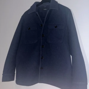 Mörkblå overshirt med knappar - Snygg mörkblå overshirt med knappar och två bröstfickor. Perfekt för lager-på-lager-stil. Långärmad design med klassisk krage.