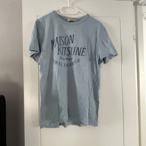 Ljusblå t-shirt från Maison Kitsuné - Säljer en stilren ljusblå t-shirt från Maison Kitsuné med tryck på framsidan. Pris kan diskuteras vid snabb affär. Hör av dig vid fler frågor👍