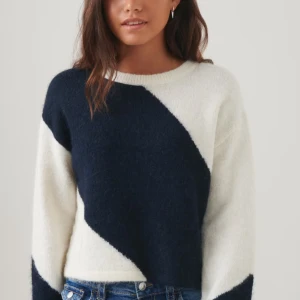 Svart och vit stickad tröja - Säljer en snygg stickad tröja i svart och vitt med ett diagonalt mönster. Tröjan har långa ärmar och en rund halsringning. Perfekt för kyligare dagar! Andvänd ensas en gång så i nyskick 