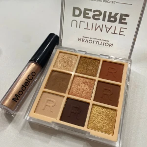 Ögonskuggspalett och flytande ögonskugga - Snygg ögonskuggspalett från Revolution med nio nyanser i varma toner, perfekt för att skapa olika looker. Inkluderar både matta och skimrande färger. Tillsammans med en flytande metallisk ögonskugga från ModelCo i en glittrande guldton.