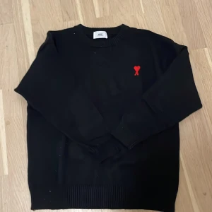  tröja  Ami Alexandre Mattiussi - Snygg svart tröja från Ami Alexandre Mattiussi med ett rött hjärta broderat på bröstet. Tröjan är köpt här på Plick. Fick ett  kvitto med men tappa bort den 