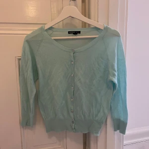 Ljusblå kofta från Mango - Säljer en söt ljusblå kofta från Mango med knappar framtill. Koftan har trekvartsärmar och en rund halsringning.