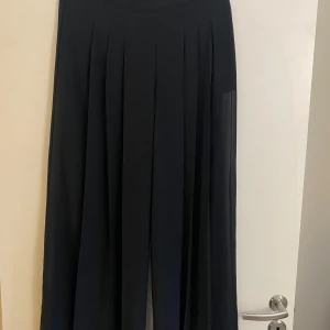 Svart byxor från Bik Bok - Elegant svarta byxor från Bik Bok med veckad design. Perfekt för en stilren look. Byxor har en klassisk passform och är tillverkad i ett lätt material som ger ett fint fall.