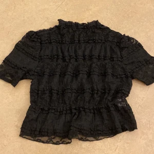 Svart blus med volanger - Säljer en jättefin svart blus. I storlek xs, har aldrig använt den, helt ny utan prislapp.