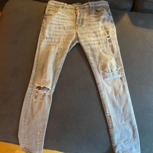 Dsquared2 Grå jeans med slitningar - Säljer ett par grå jeans med coola slitningar och en snygg tvätt. De har en klassisk femficksdesign och en knappgylf. Perfekta för en avslappnad stil.