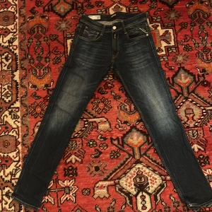 Mörkblå jeansbyxor från Replay - Snygga mörkblå Replay Anbass jeans med slim fit. Klassisk femficksdesign och knapp och draggylf. Perfekta för en stilren look. I storlek 28. I bra skick.