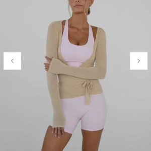 Beige långärmad omlottopp - Snygg beige långärmad omlottopp med knytning i midjan från exercere . Perfekt för en stilren och bekväm look. Passar bra till både träning och vardag. Ny pris 758 kr använd en gång.