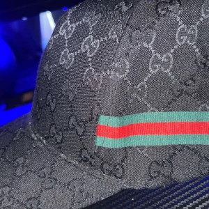 Svart keps med mönster och ränder - Snygg svart keps med diskret mönster och ikoniska ränder i grönt och rött. Perfekt för att ge en stilren touch till din outfit.