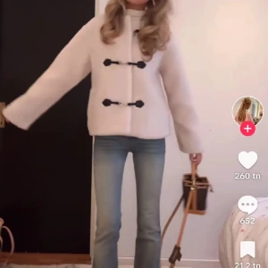 Beige teddyjacka med knäppning - Mysig beige teddyjacka från Gina med unik knäppning framtill. Jackan har en rund hals och långa ärmar, perfekt för kyligare dagar. Den fluffiga texturen ger en trendig look som är både bekväm och stilren.