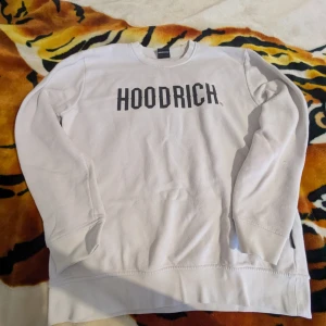 Vit sweatshirt från Hoodrich - Säljer en vit sweatshirt från Hoodrich med svart text på bröstet. Tröjan har långa ärmar och en klassisk rund halsringning. Perfekt för en avslappnad stil. Hör av dig vid intresse!