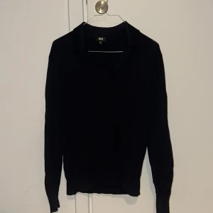 Merinopiké från Uniqlo - Säljer en stilren mörkblå tröja från Uniqlo. Tröjan har en klassisk krage och långa ärmar, perfekt för en minimalistisk look. Den är tillverkad i ett mjukt material som ger en bekväm passform. Passar bra till både vardag och mer uppklädda tillfällen.