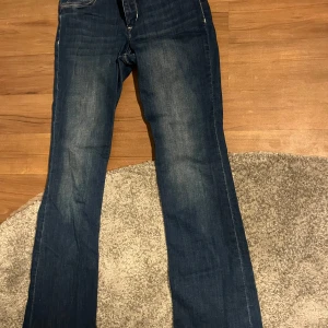 Blå bootcut jeans - Snygga blå bootcut jeans i denim. Perfekta för en avslappnad stil med klassisk femficksdesign och knappgylf. Passar bra till både sneakers och stövlar.