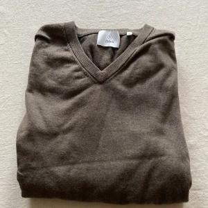 Brun tröja från Bläck - Säljer en stilren brun tröja från Bläck med v-ringning. Perfekt för en avslappnad men ändå snygg look. Tröjan har långa ärmar och ribbade muddar vid ärmslut och nederkant.