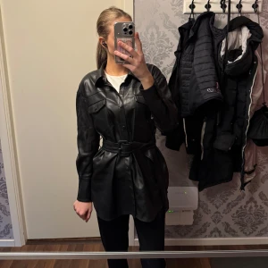 Svart lång skinnjacka  - Fin lång svart skinn jacka. Använd väldigt få gånger så är i princip som ny.